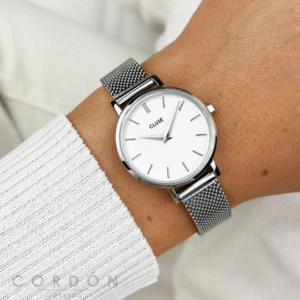 Reloj Cluse de mujer redondo plateado con malla puesto en la muñeca